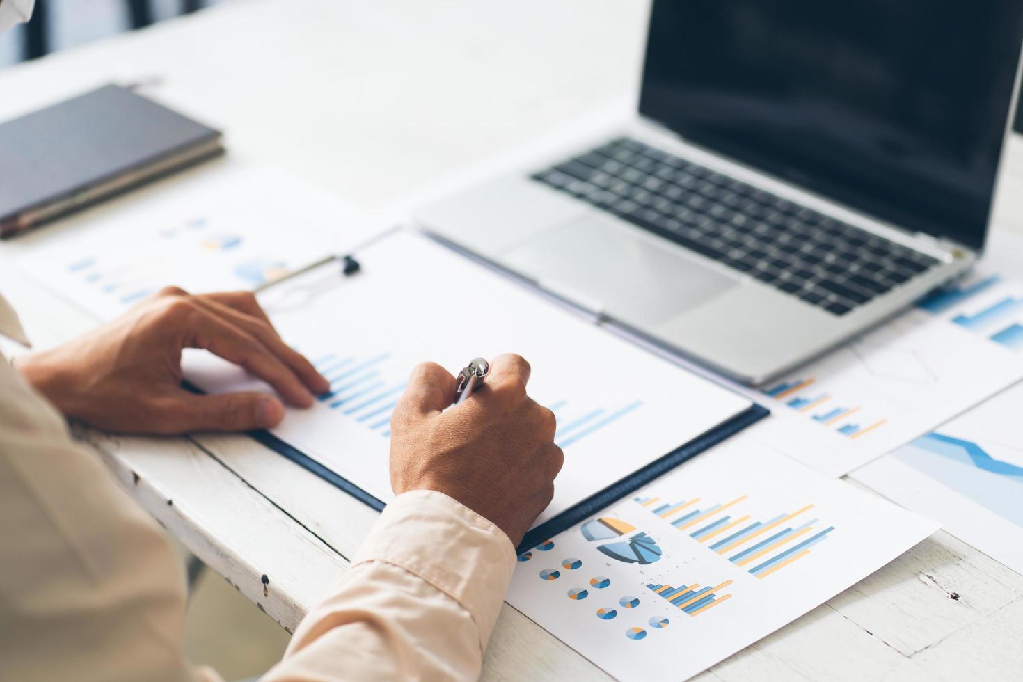 businessman use calculator and computer holding paper work with pen on desk in office. finance and accounting concept photo