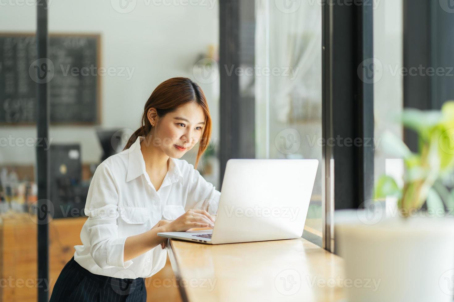 hermosa linda joven empresaria asiática en el café, usando computadora portátil. foto