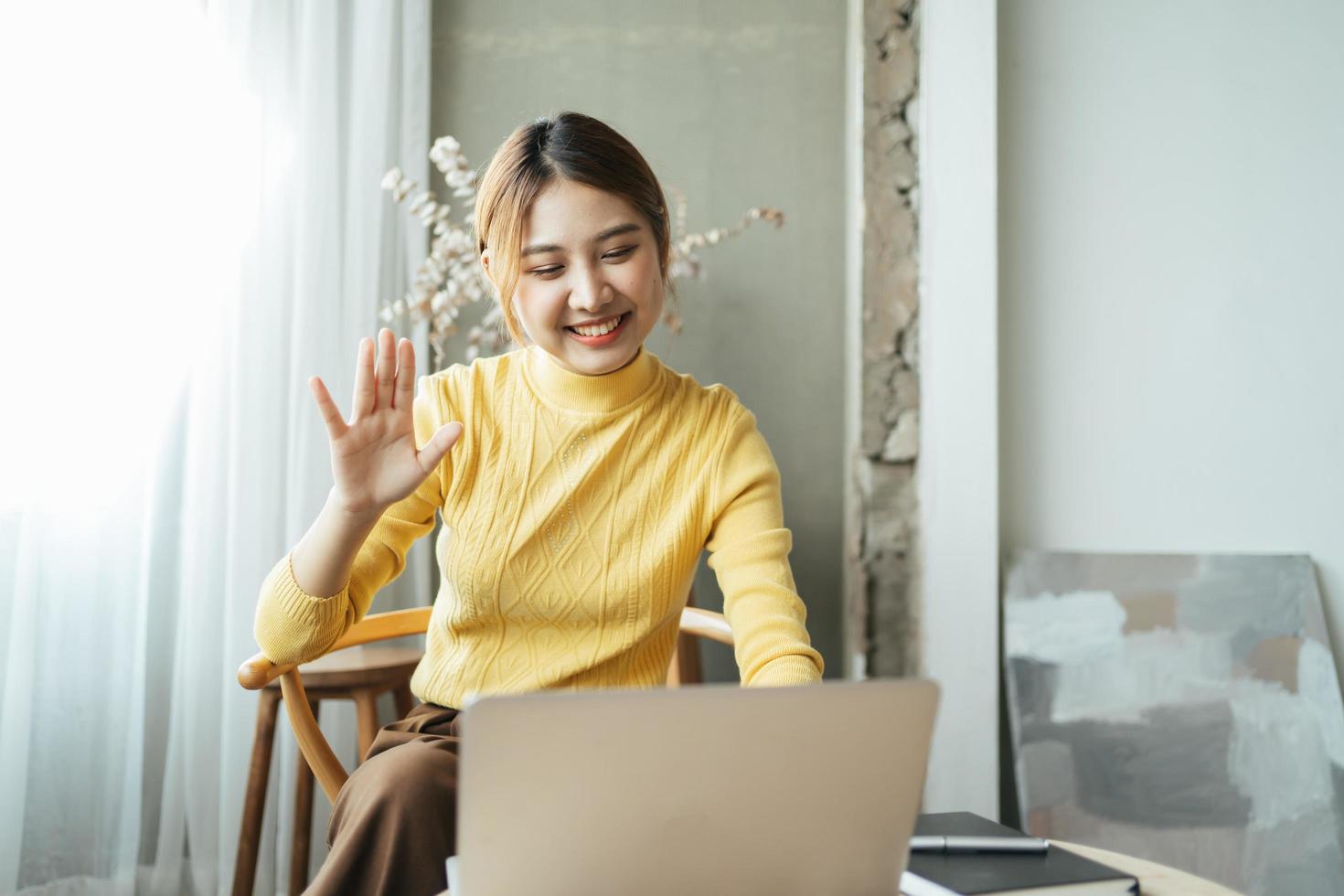 Asian woman having video call on her computer at home. Smiling girl studying online with teacher. photo