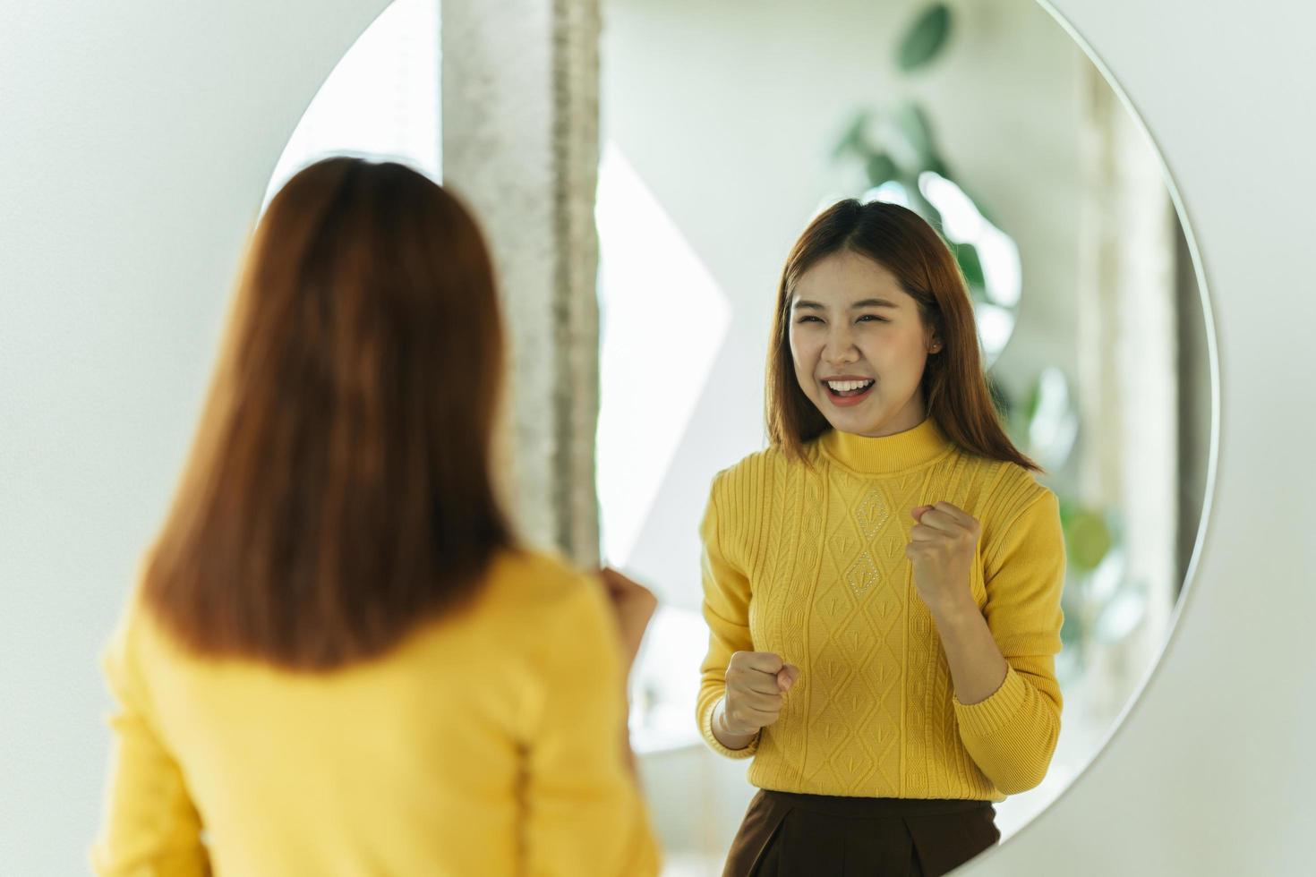 A young Asian woman talks to herself through a mirror to build her self-confidence and empower herself. photo