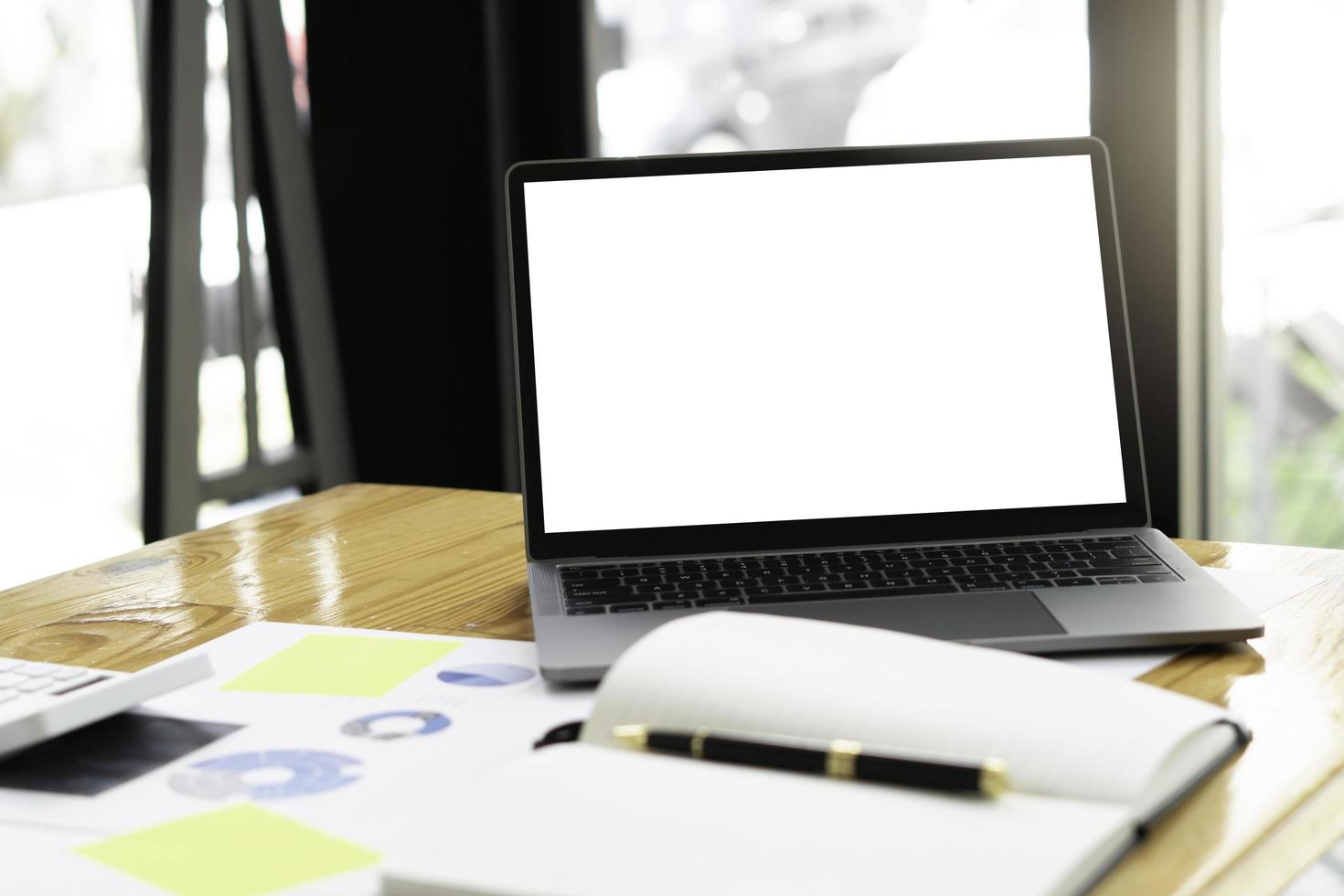 Side view of contemporary workplace with laptop computer, notebook, coffee cup and stationery on wooden table. clipping path. photo