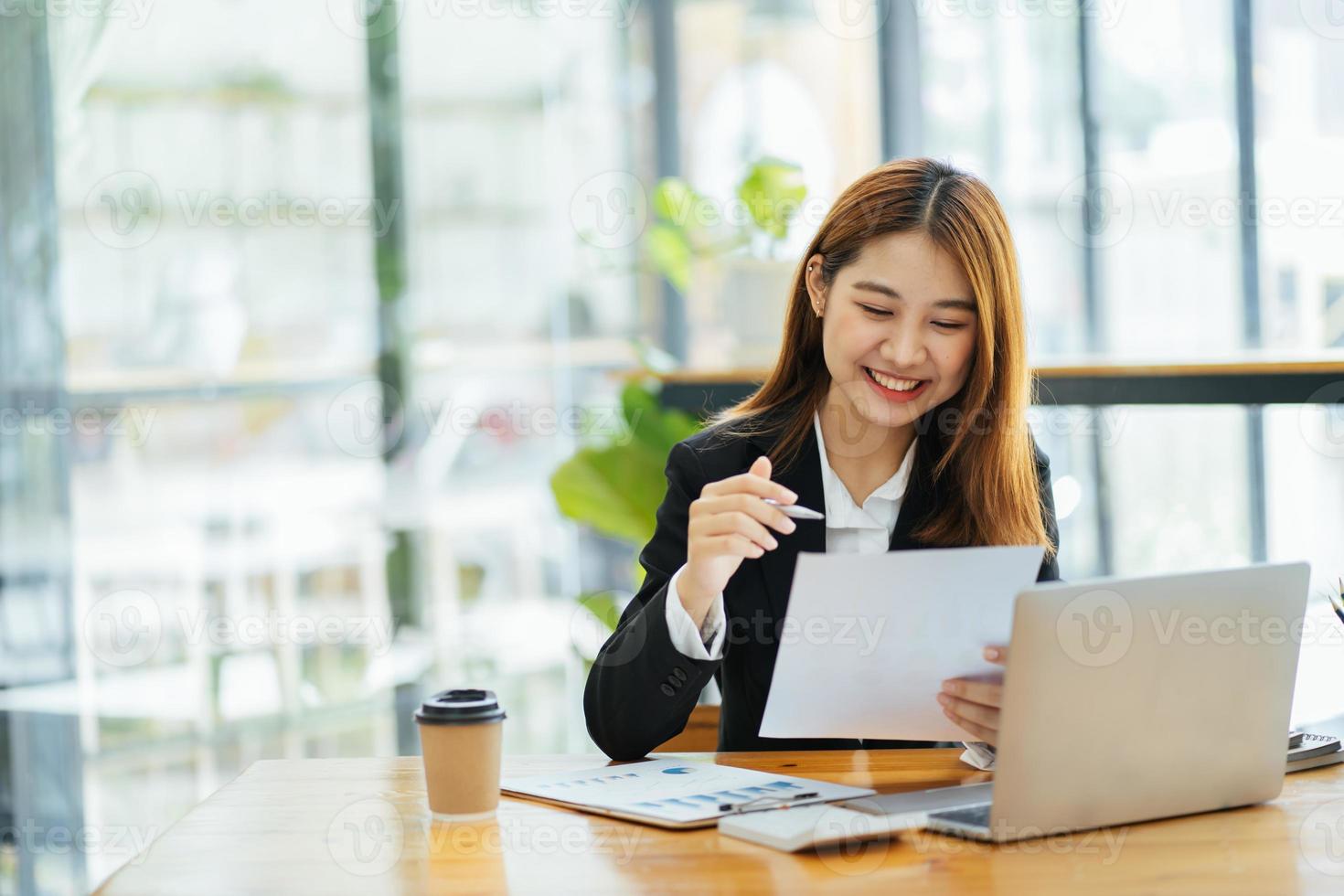 Portrait of Asian young female working on laptop and financial report at office. photo