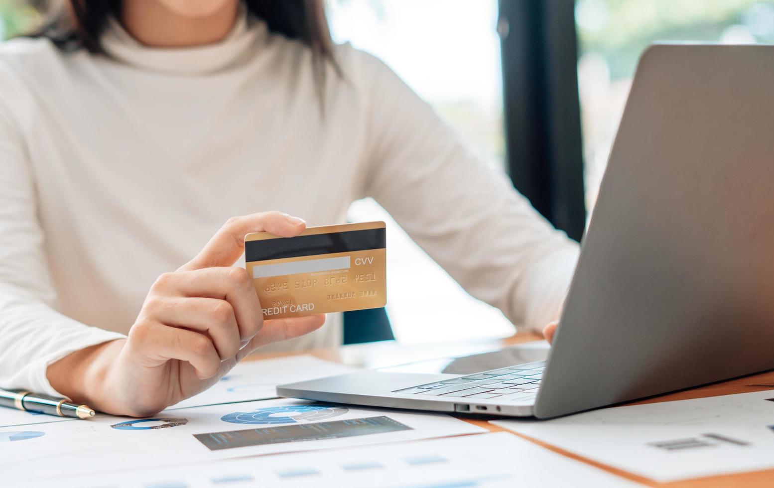 mano de mujer con tarjeta de crédito y usando una computadora portátil en casa, hombre de negocios o empresario trabajando, compras en línea, comercio electrónico, banca por Internet, gastando dinero, trabajando desde el concepto de casa foto