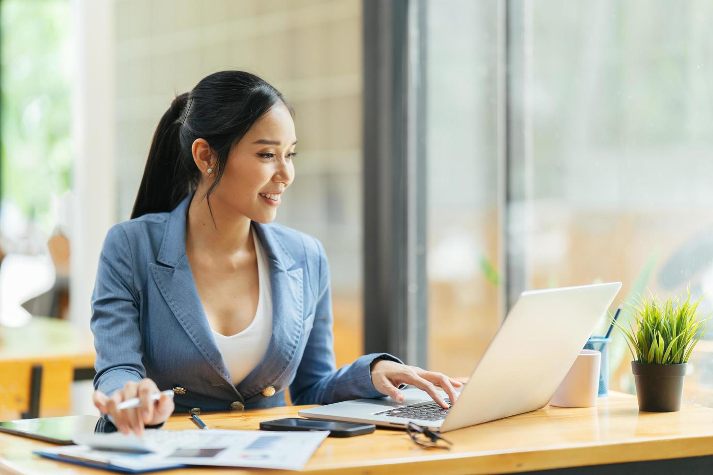 Asian female talking about sale report in video conference. Asian team using laptop and tablet online meeting in video call.Working from home remotely. photo