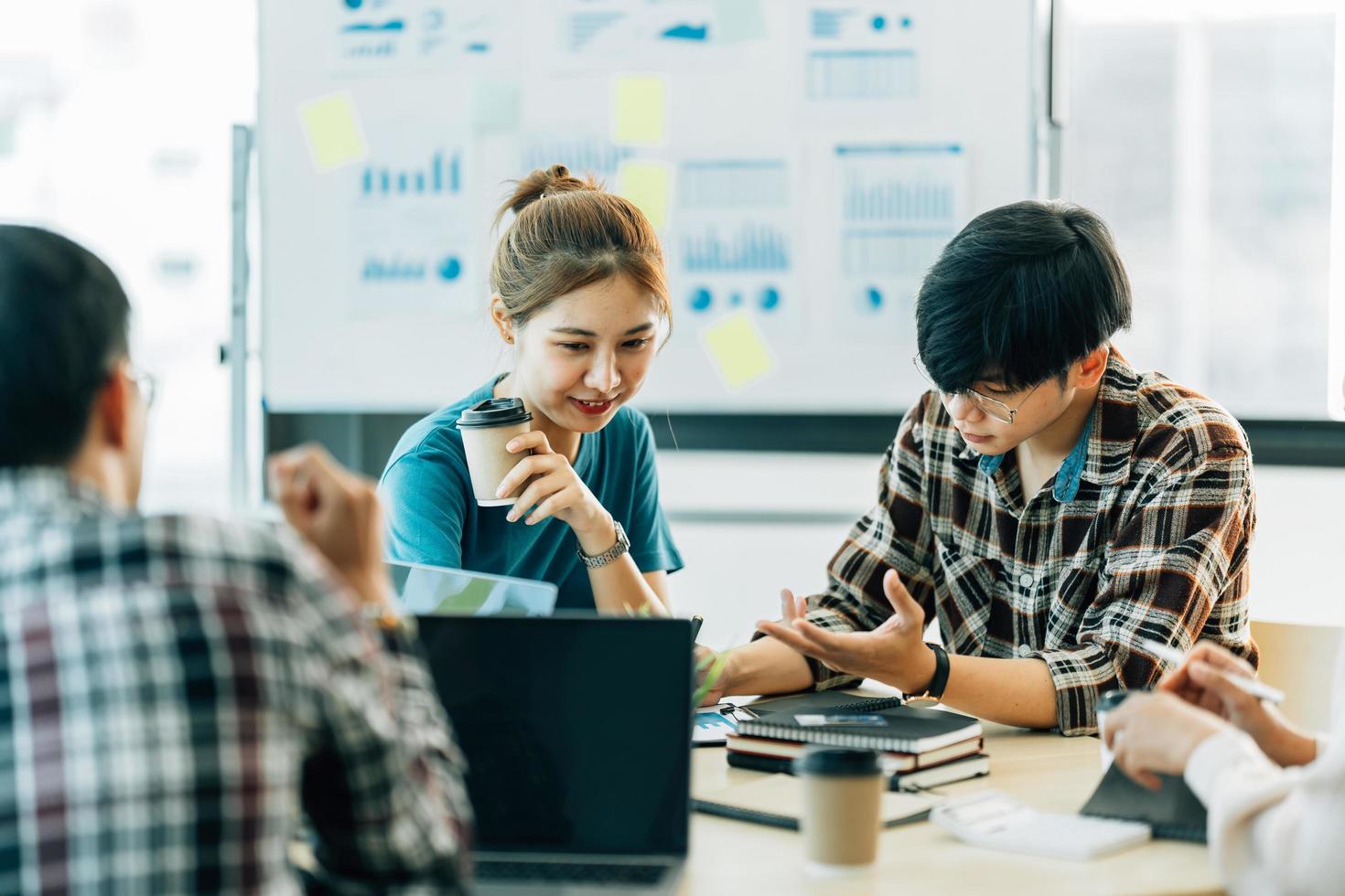 grupo de cuatro felices jóvenes compañeros de equipo de personas corporativas asiáticas que se reúnen para discutir negocios en la oficina. foto