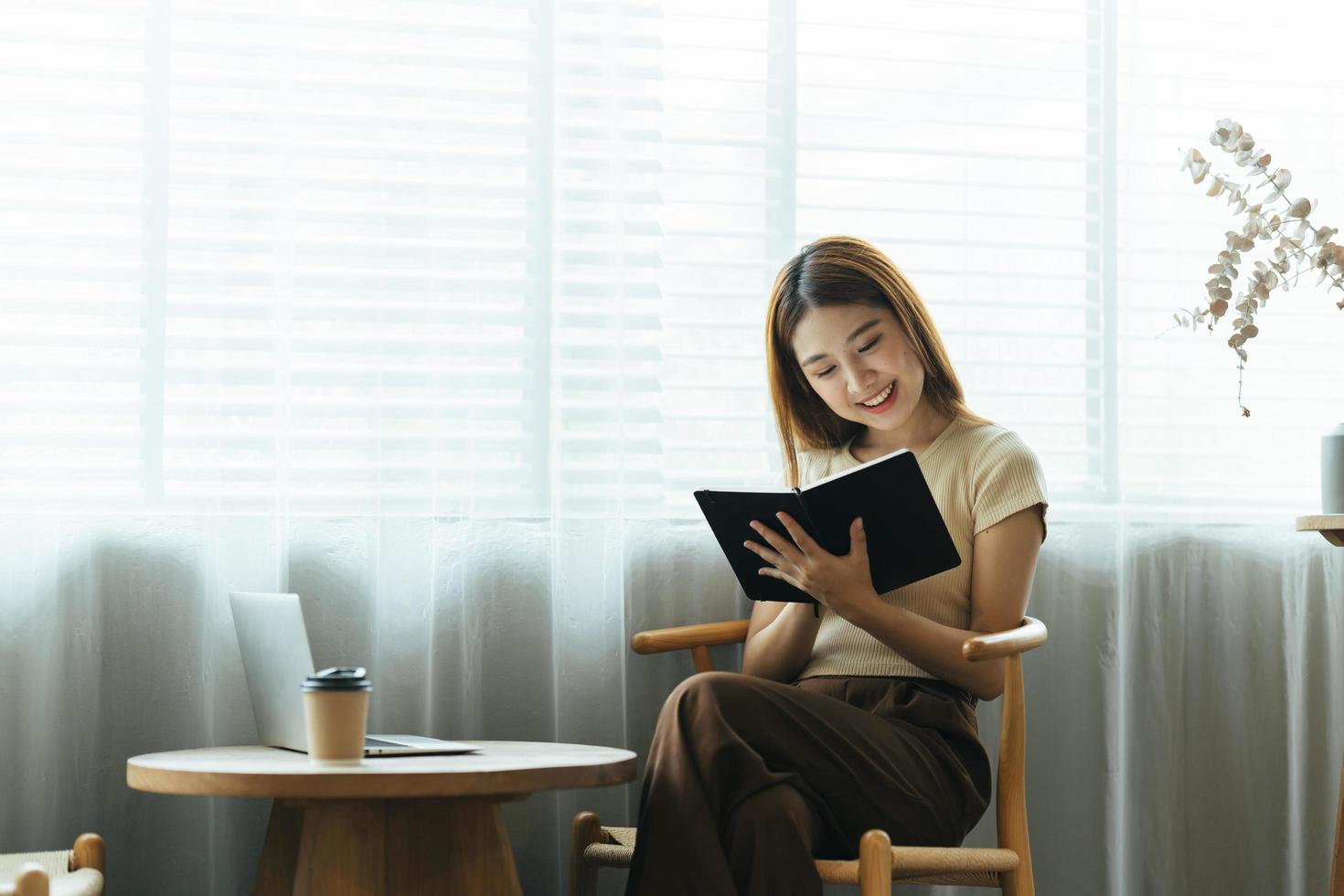 Young asian business woman is sitting at a desk and taking notes in a notebook. The concept of education and technology. photo