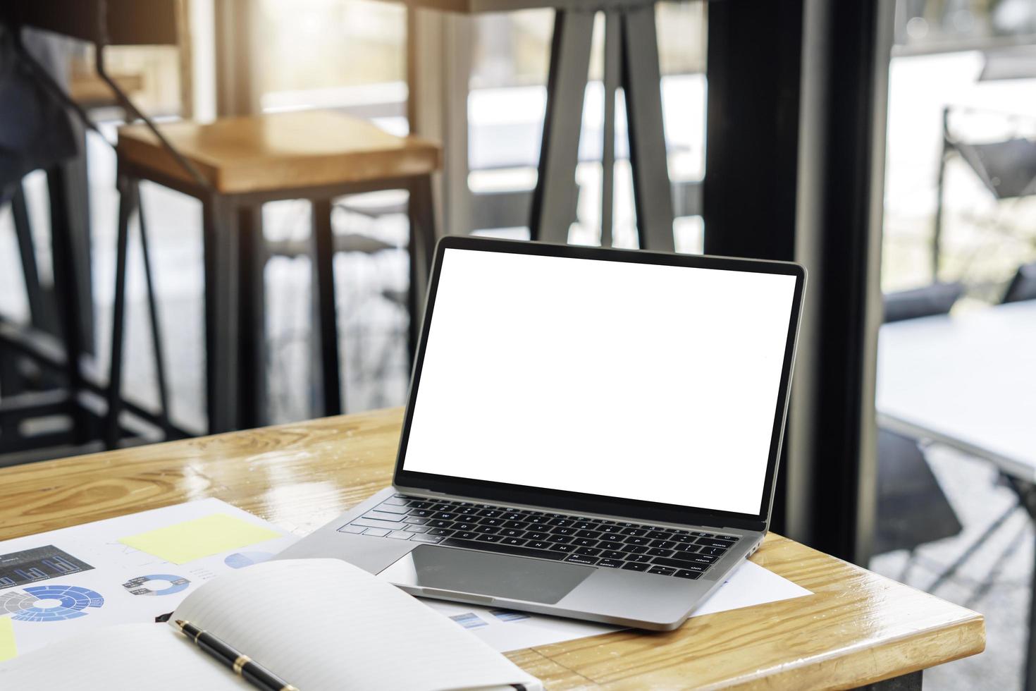 Side view of contemporary workplace with laptop computer, notebook, coffee cup and stationery on wooden table. clipping path. photo