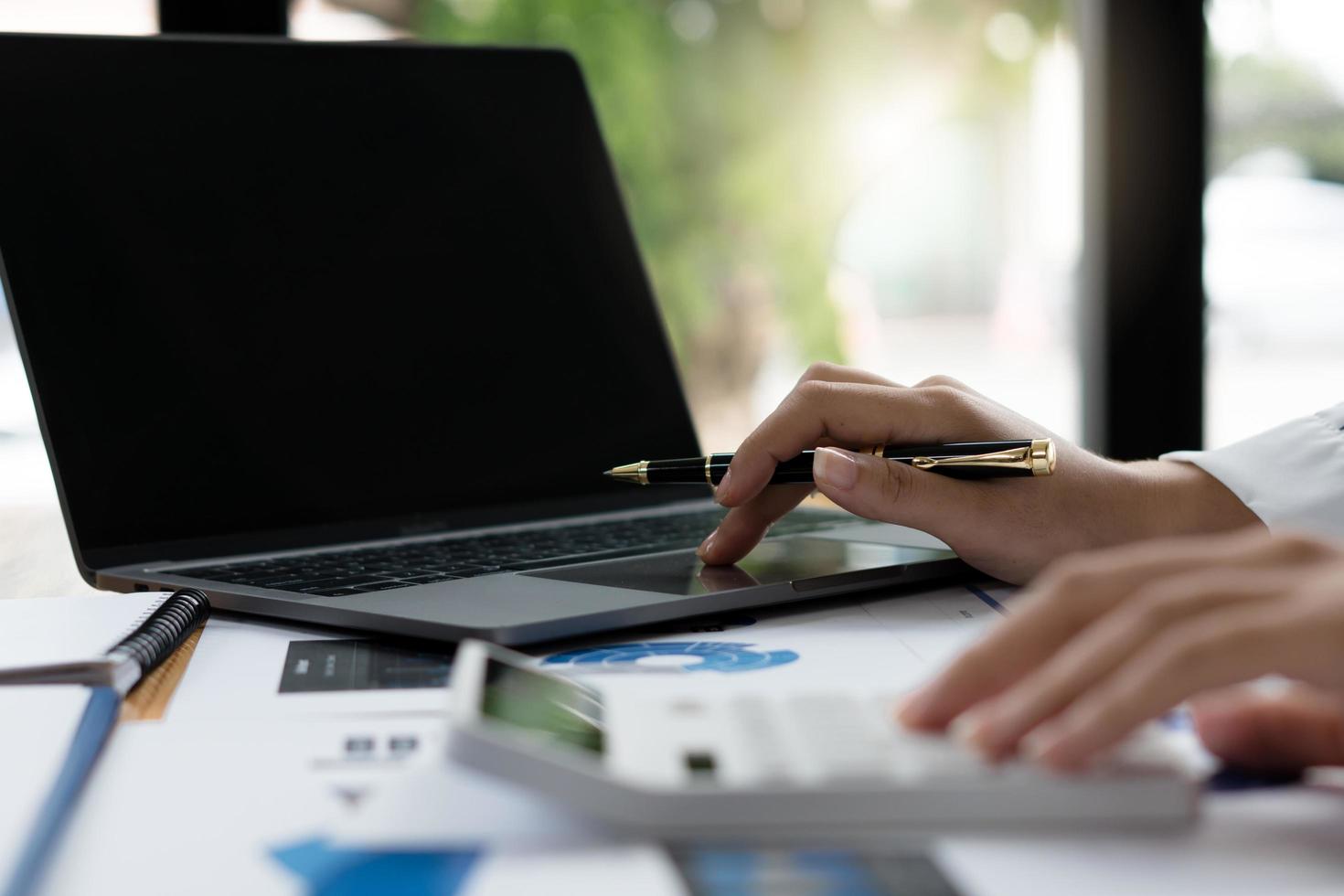 Close up of businessman or accountant working on laptop computer for calculate business data, accounting document and calculator at office, business concept photo