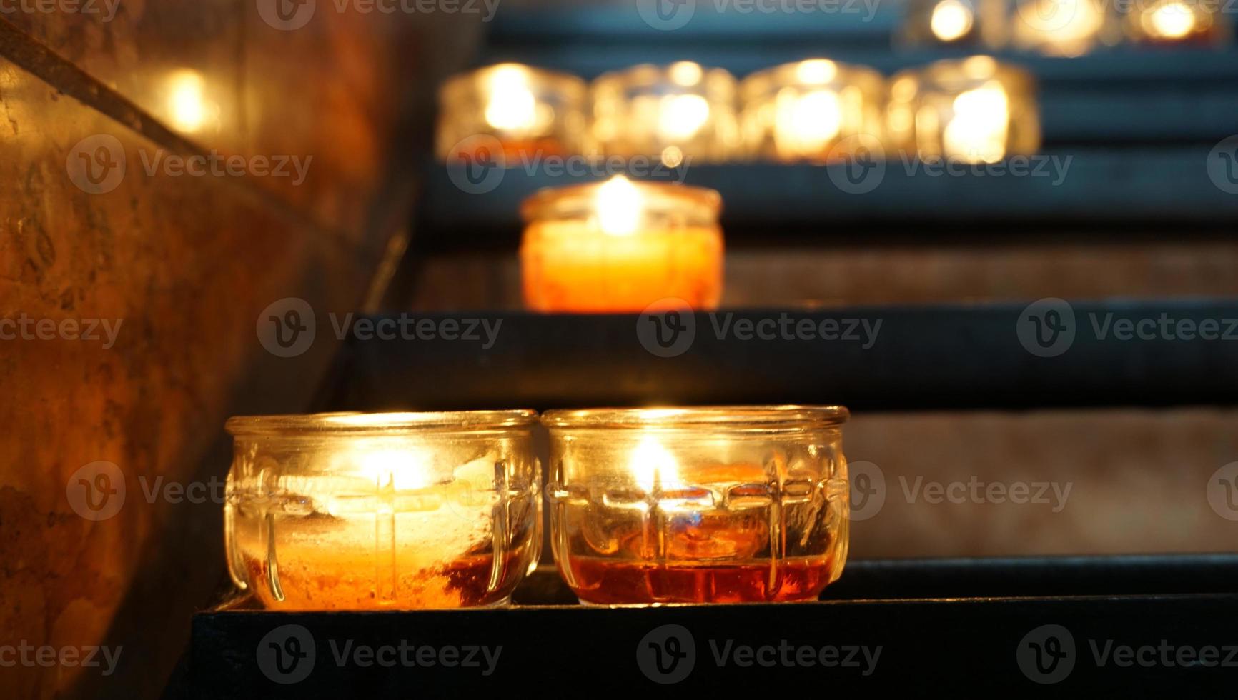 vela e iluminación en el estante por la noche en la iglesia, oren por la paz foto