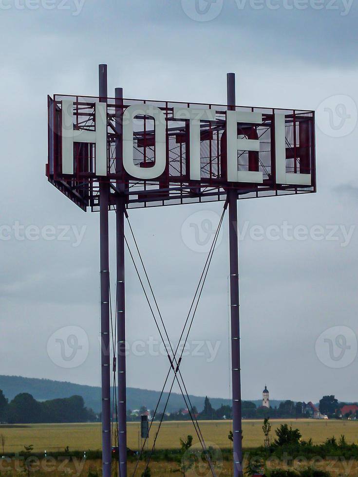 Vertical shot of a Hotel sign on a pole against a blue cloudy sky during the daytime photo