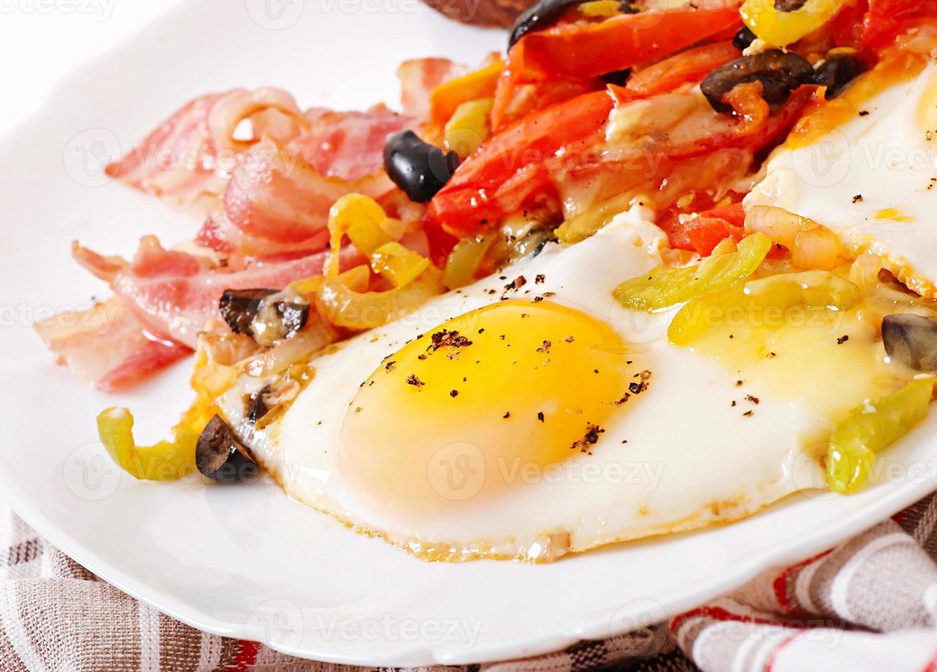 Breakfast - fried eggs with bacon, tomatoes, olives and slices of cheese photo