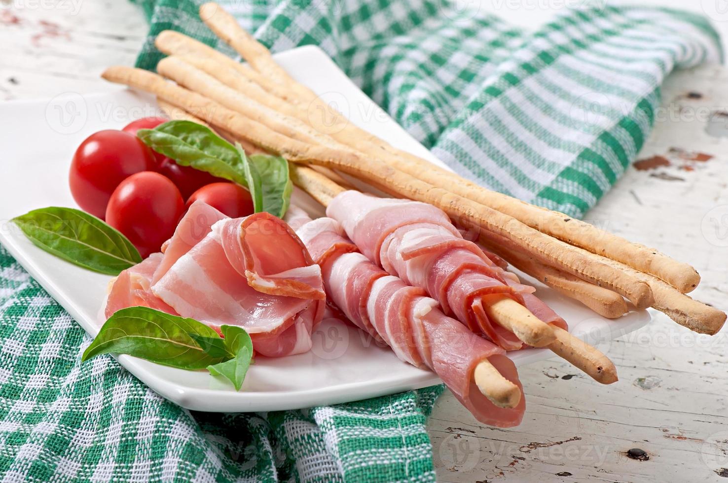 Grissini bread sticks with ham, tomato and basil photo