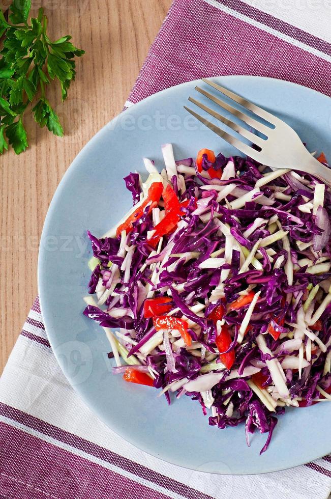 Salad of red and white cabbage and sweet red pepper, seasoned with lemon juice and olive oil in wooden bowl photo