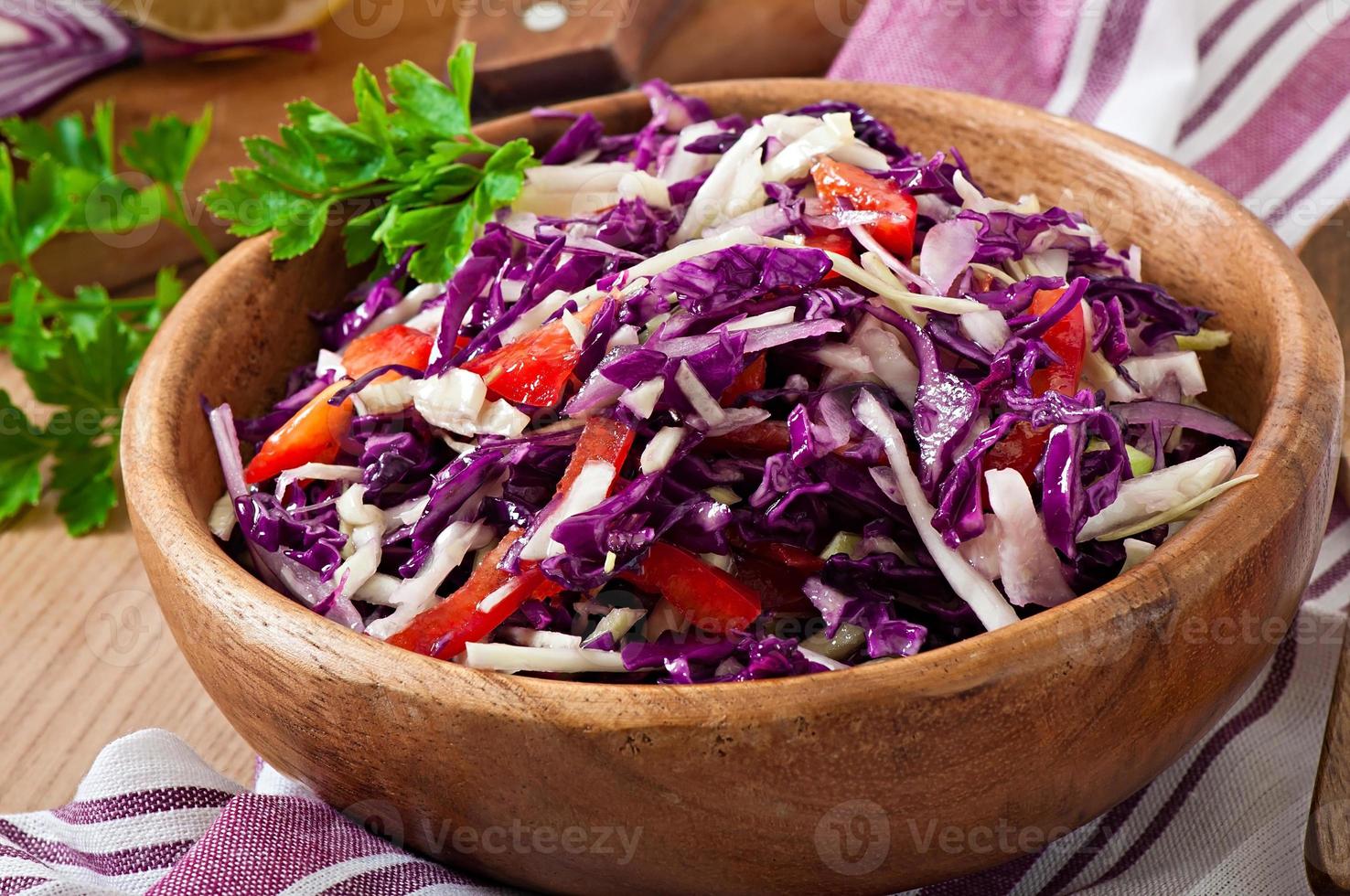 Salad of red and white cabbage and sweet red pepper, seasoned with lemon juice and olive oil in wooden bowl photo