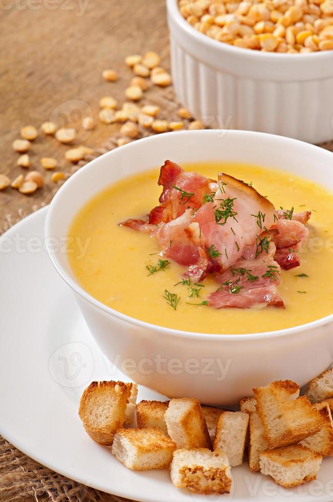 Cream soup of peas with fried bacon and croutons photo