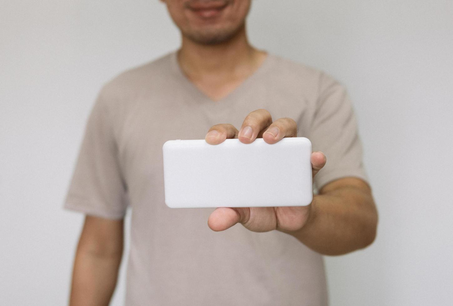 Close up man holding white power bank. man wearing brown shirt holding energy reserves. photo