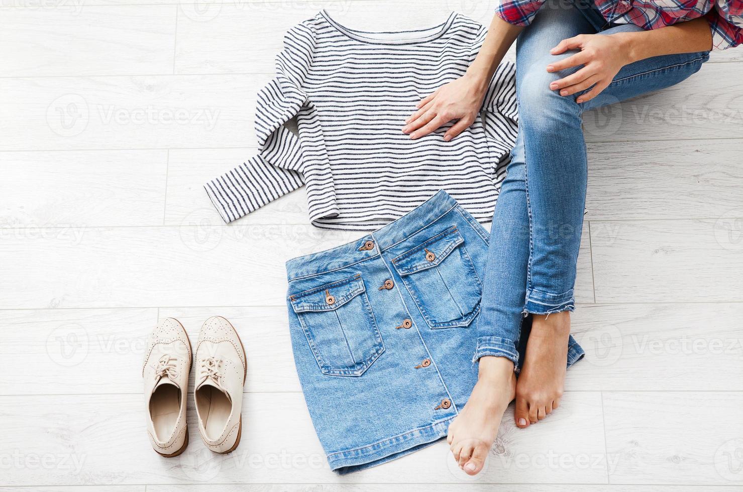 Casual summer outfit with different accessories and female legs in jeans on white wooden floor. Top view and copy space. photo