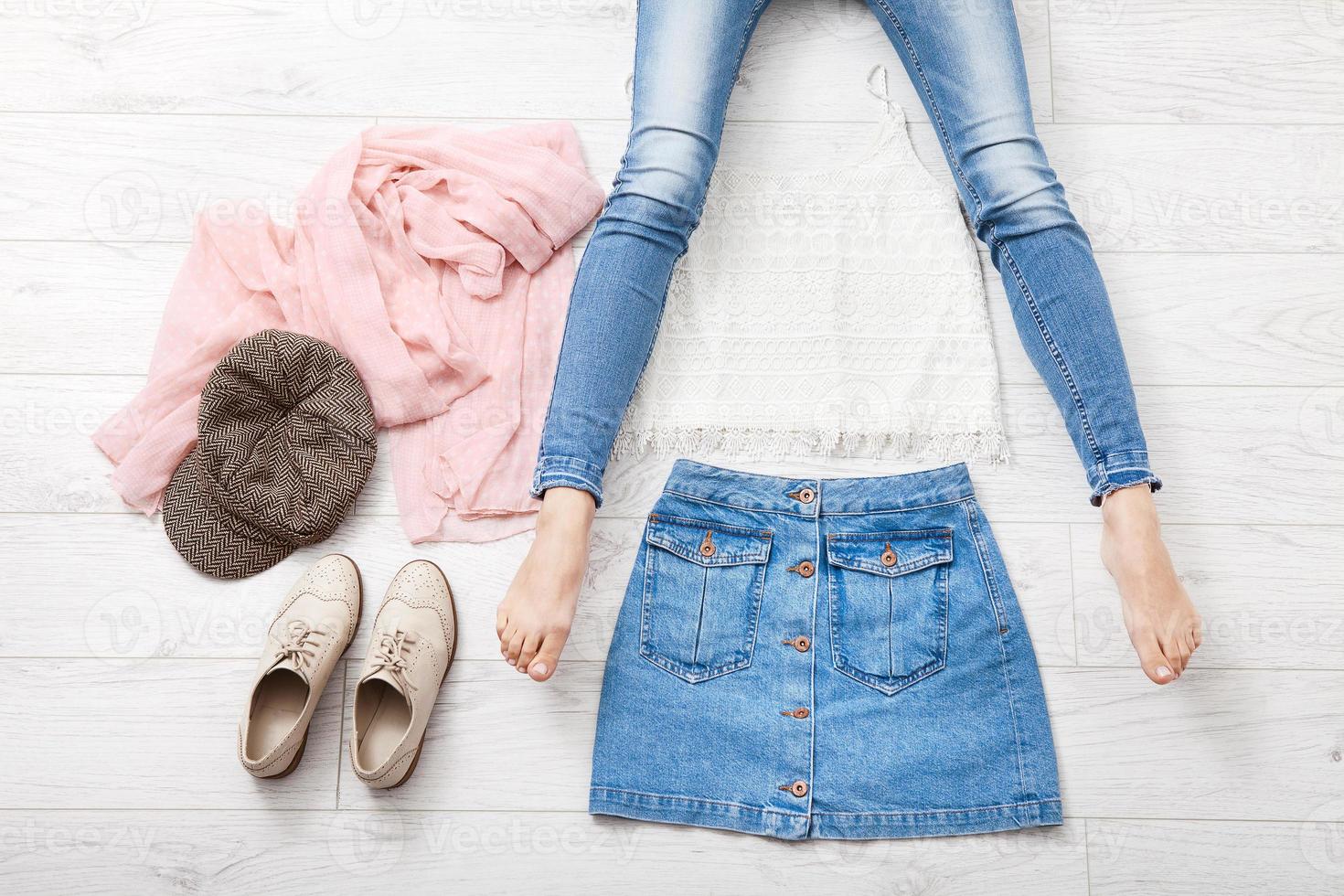 Casual summer outfit with different accessories and female legs in jeans on white wooden floor. Top view and copy space. photo