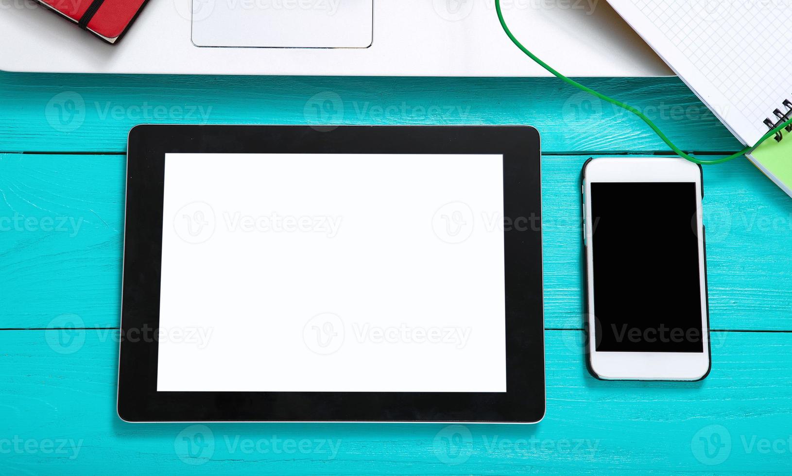 Tablet and mobilephone with copy space on screens. Blue wooden background and top view photo