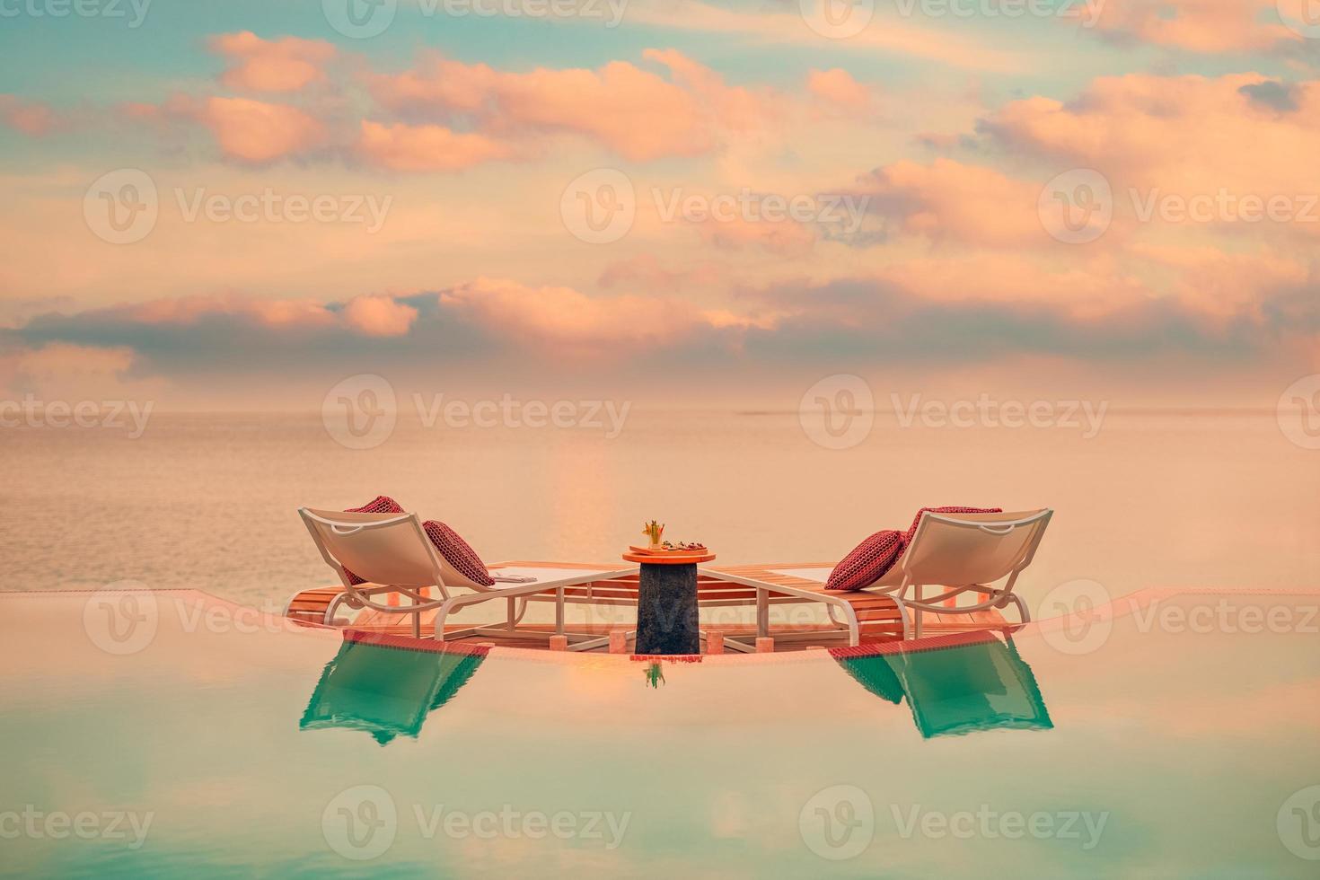 vista del paisaje marino bajo la luz del atardecer con mesa de comedor con piscina infinita alrededor. escapada tropical romántica para dos, concepto de pareja. sillas, comida y romance. comedor de destino de lujo, plantilla de luna de miel foto