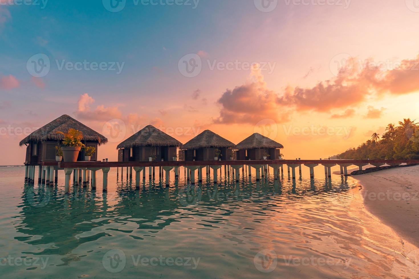 Amazing sunset panorama at Maldives. Luxury resort villas seascape with soft led lights under colorful sky. Beautiful twilight sky and colorful clouds. Beautiful beach background for vacation holiday photo