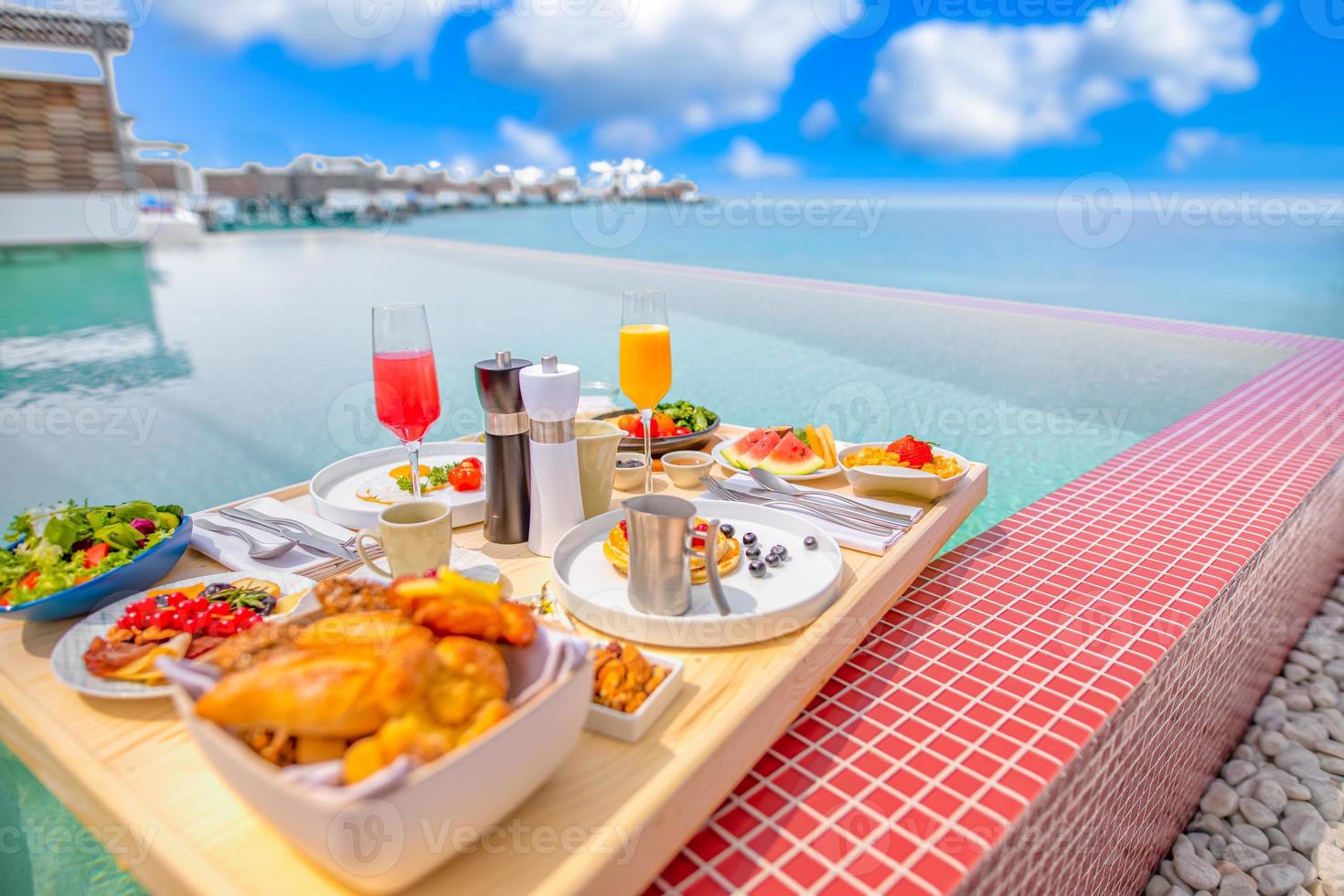 Breakfast in swimming pool, floating breakfast in tropical resort. Table relaxing in calm pool water, healthy breakfast and fruit plate by resort pool. Exotic summer diet luxury island beach lifestyle photo