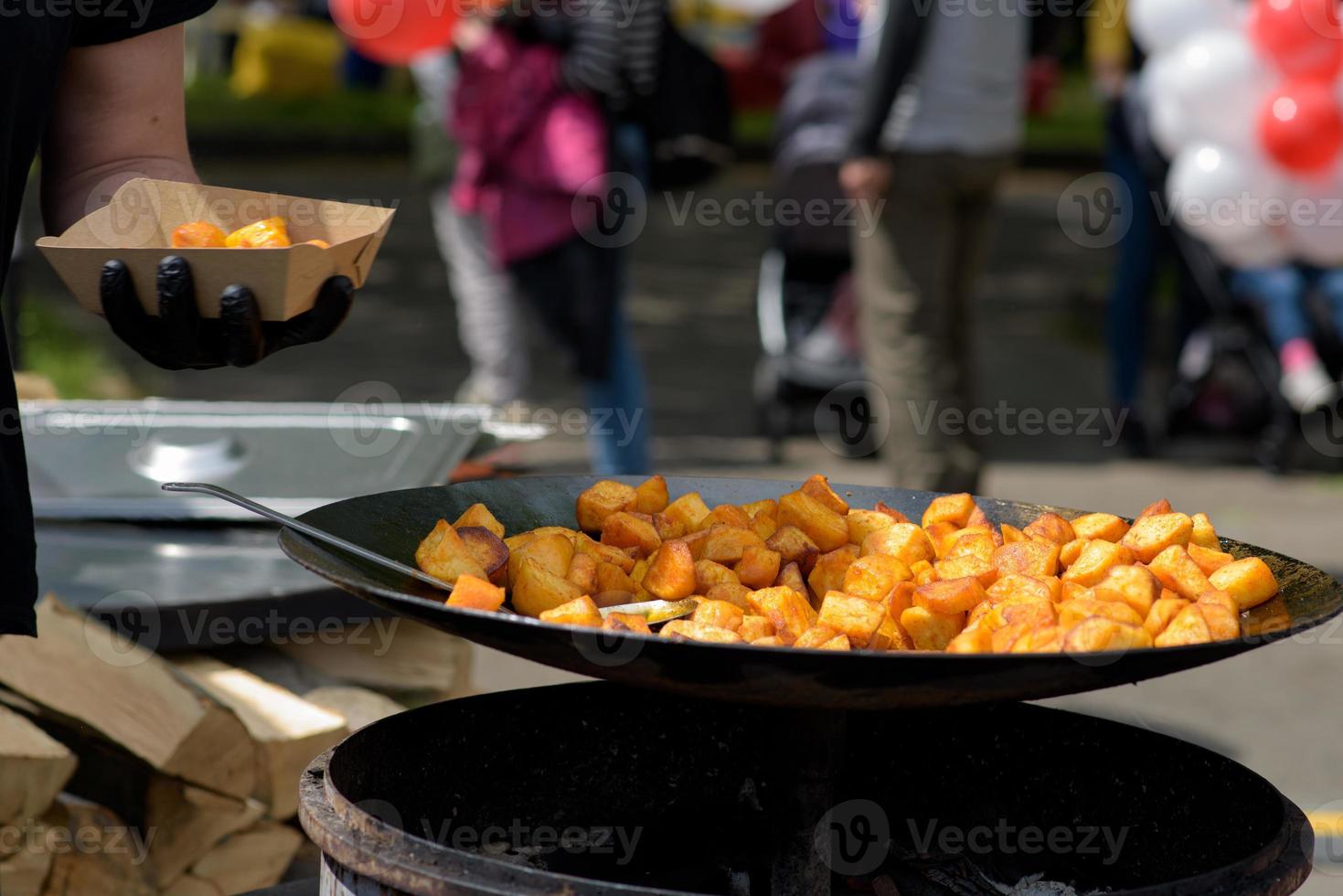 trozos de patatas fritas en una sartén grande durante el festival de comida callejera. foto