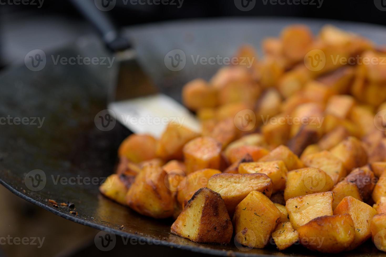 Chunks of fried potatoes in a large skillet during the street food festival. photo