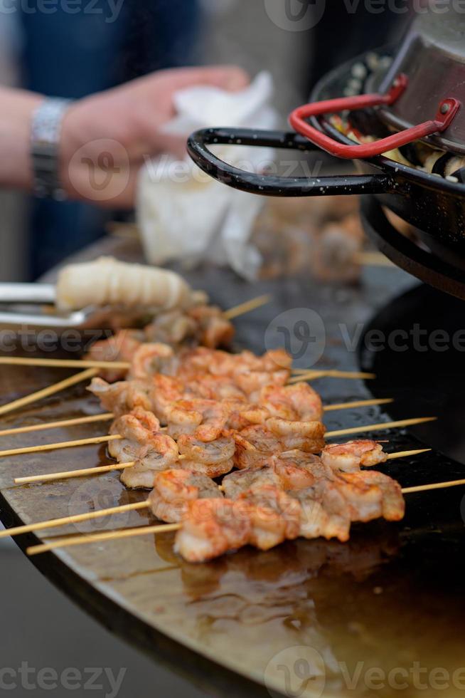 Cooking shrimp, prawn skewers on grill at street food festival - close up photo