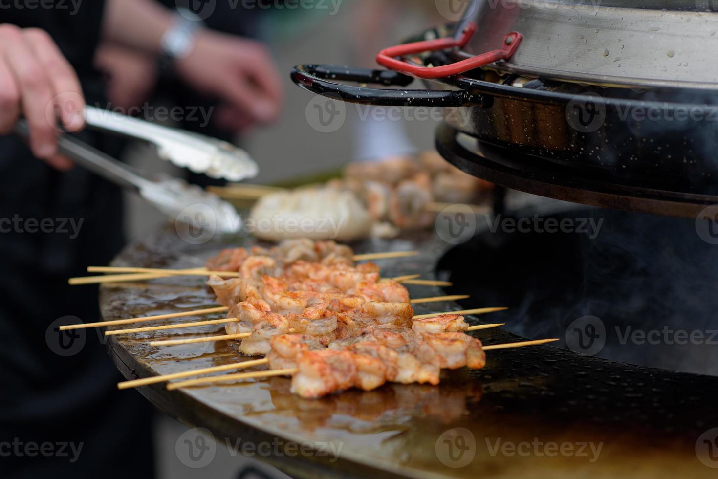 Cooking shrimp, prawn skewers on grill at street food festival - close up photo