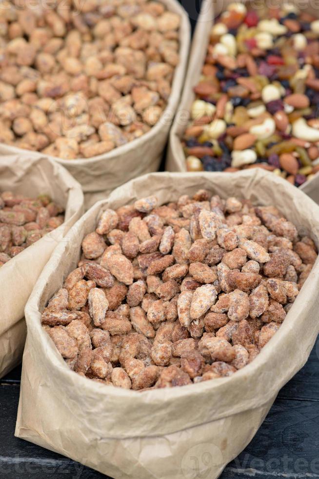 las almendras y los pistachos con especias se encuentran en bolsas de papel en el mostrador. foto