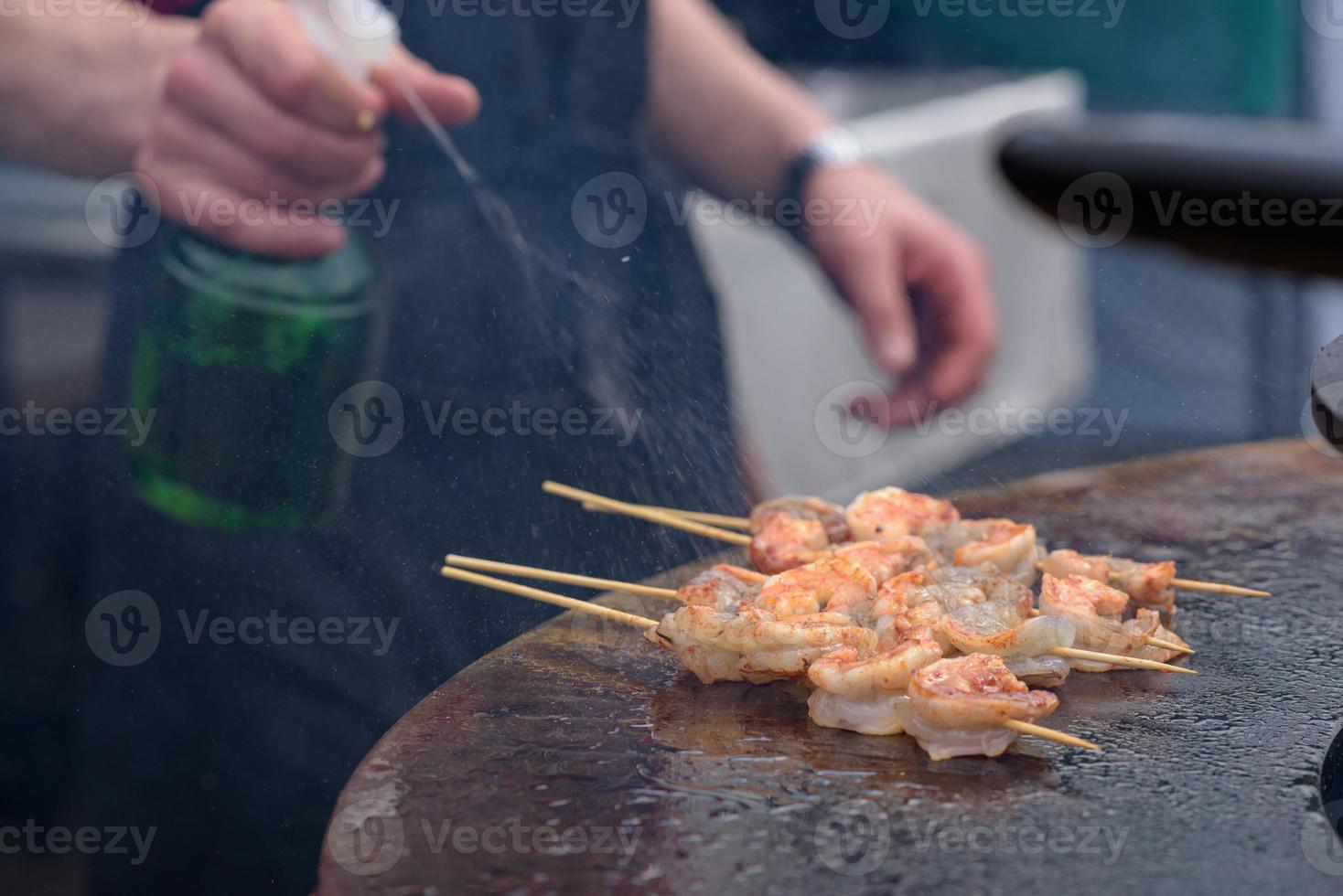 Cooking shrimp, prawn skewers on grill at street food festival - close up photo