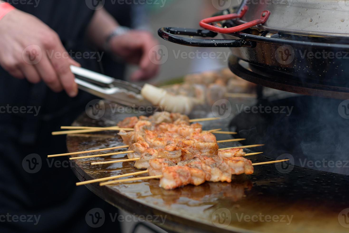 Cooking shrimp, prawn skewers on grill at street food festival - close up photo