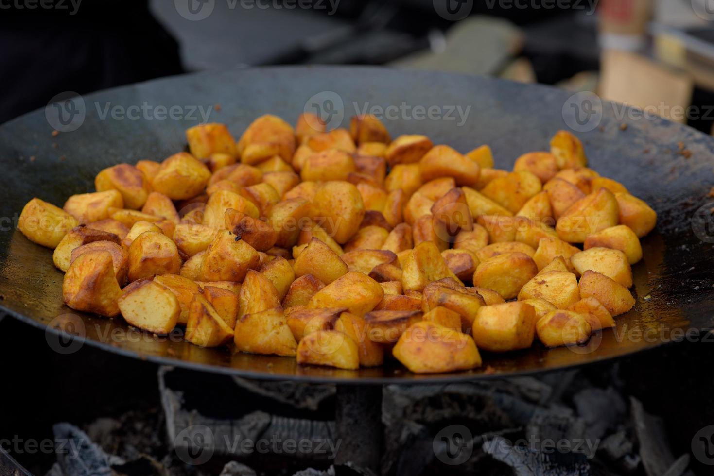 Chunks of fried potatoes in a large skillet during the street food festival. photo