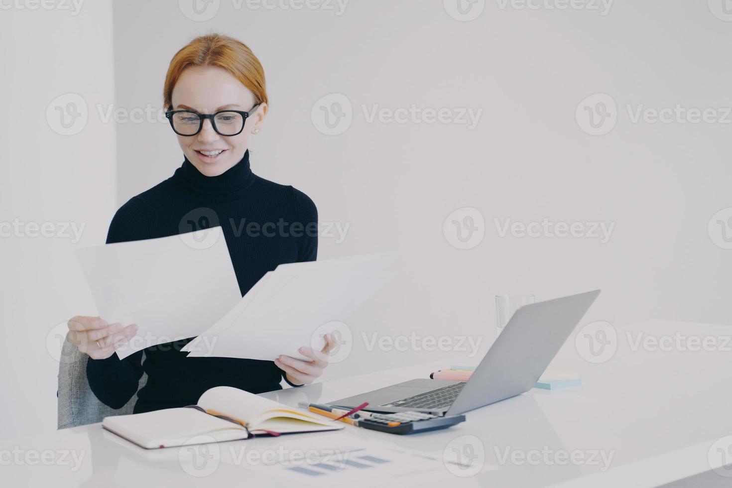Happy european business lady is doing paperwork and smiling. Concept of business success. photo