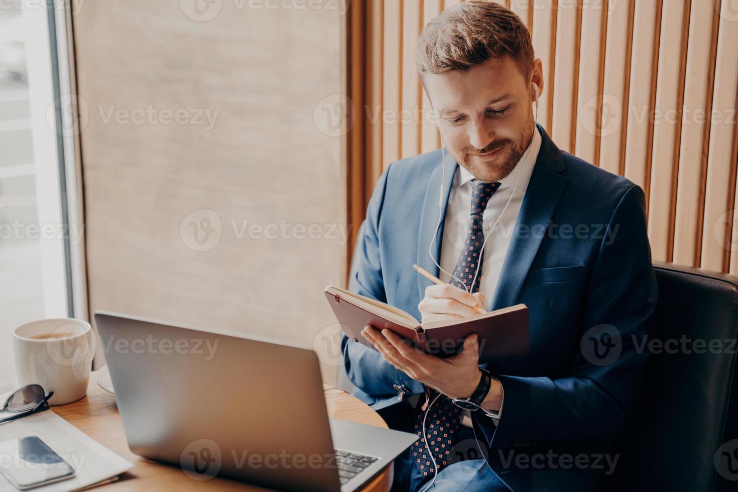 empresario guapo sin afeitar en traje sentado con una computadora portátil en el café foto