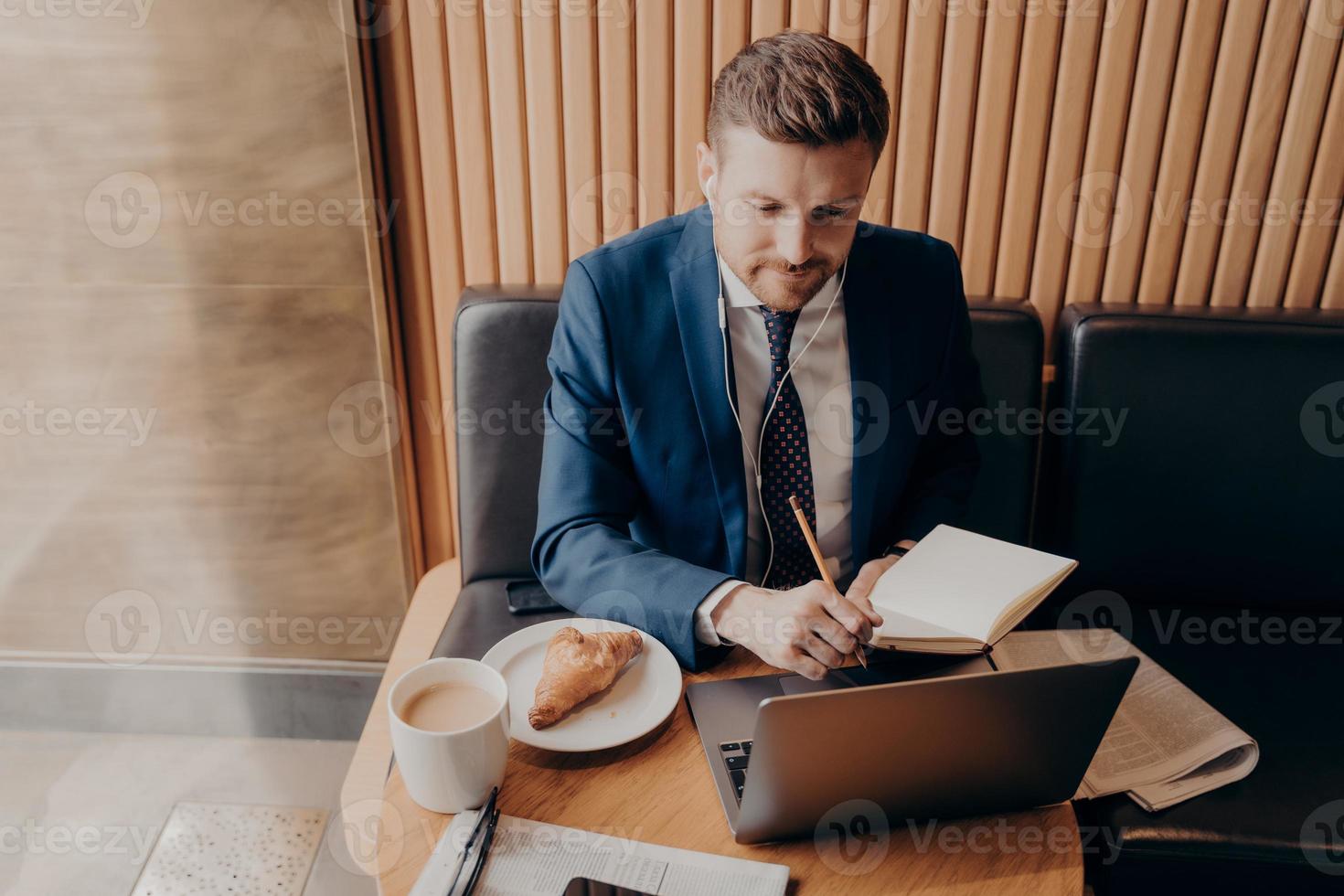 Male business executive watching webinar on laptop in restaurant photo