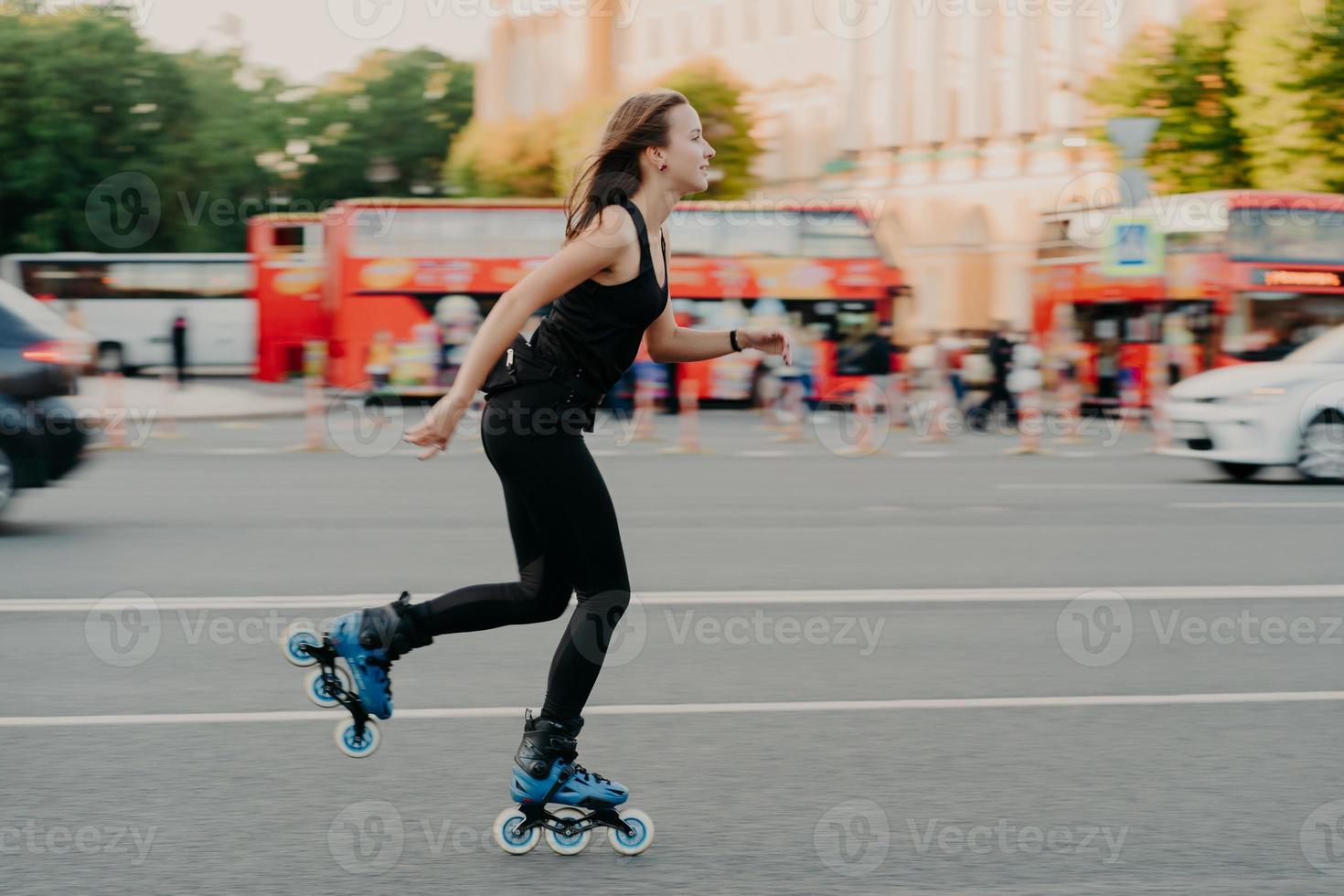 Outdoor activities for being healthy and fit. European woman in good physical shape rides on rollers rolleblades on inline skates dressed in active wear has active rest. Sporty lifestyle concept photo