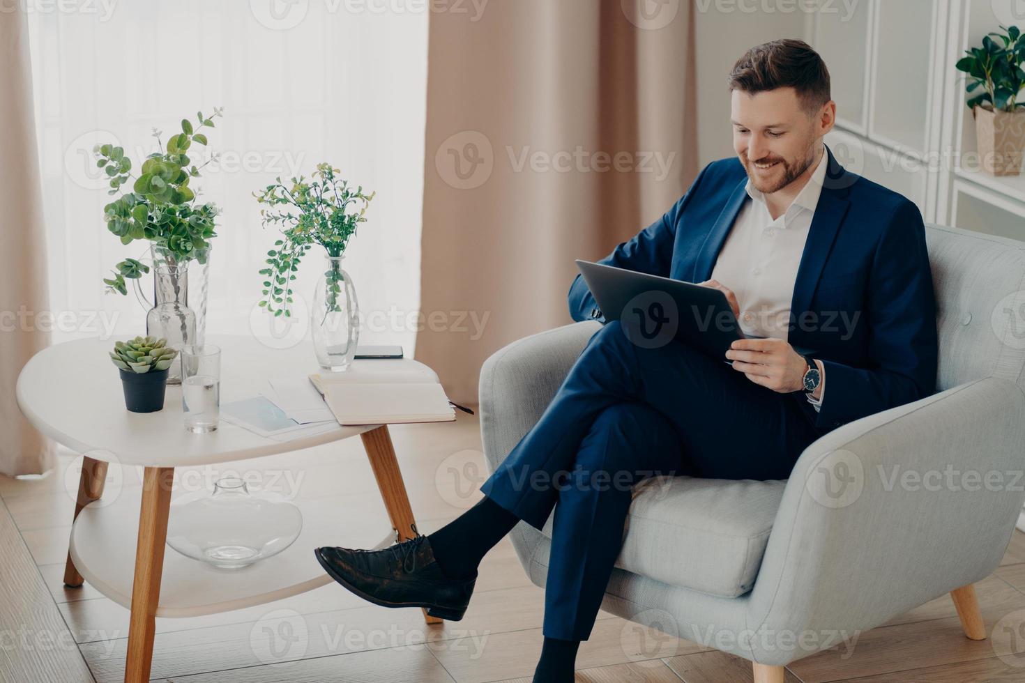 Happy businessman working on his computer in living room photo