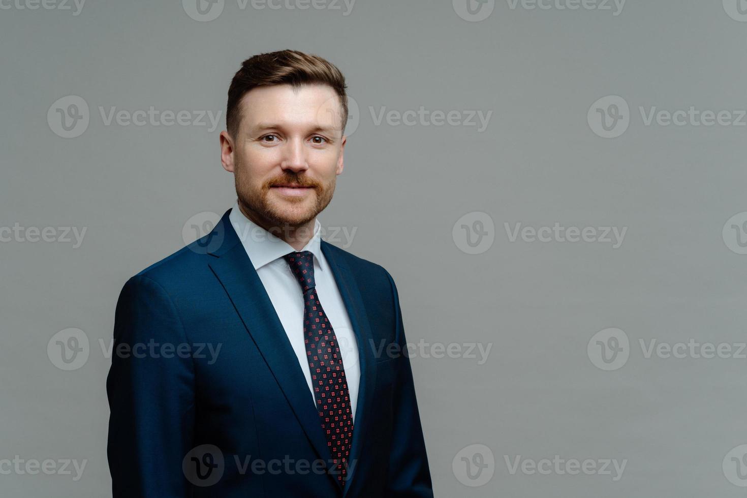 Confident male CEO in formal outfit has good business reputation looks smart at work isolated over grey studio backgrounf with copy space for your promotion. Charismatic employer poses indoor photo