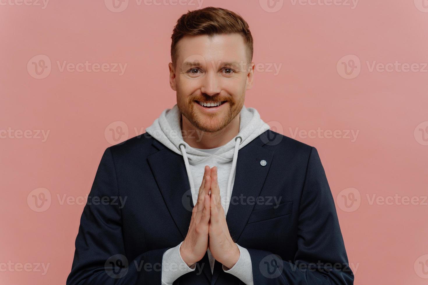 Positive handsome man praying to god, asking for help or making wish photo