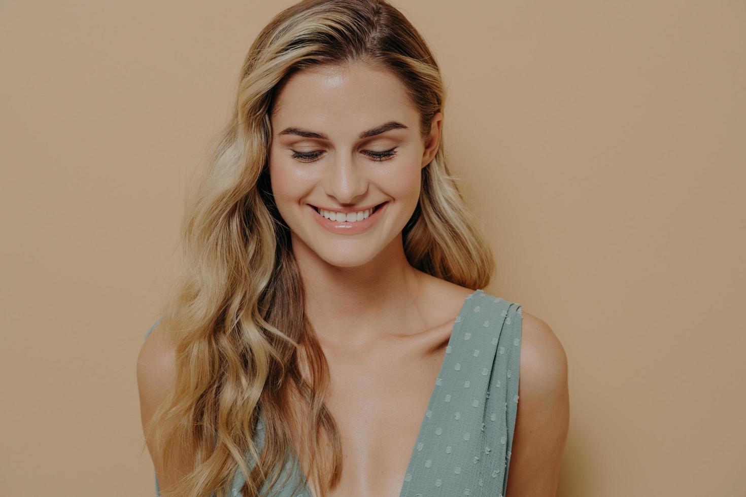 tímida tímida joven bonita mujer rubia mirando hacia abajo con una sonrisa foto