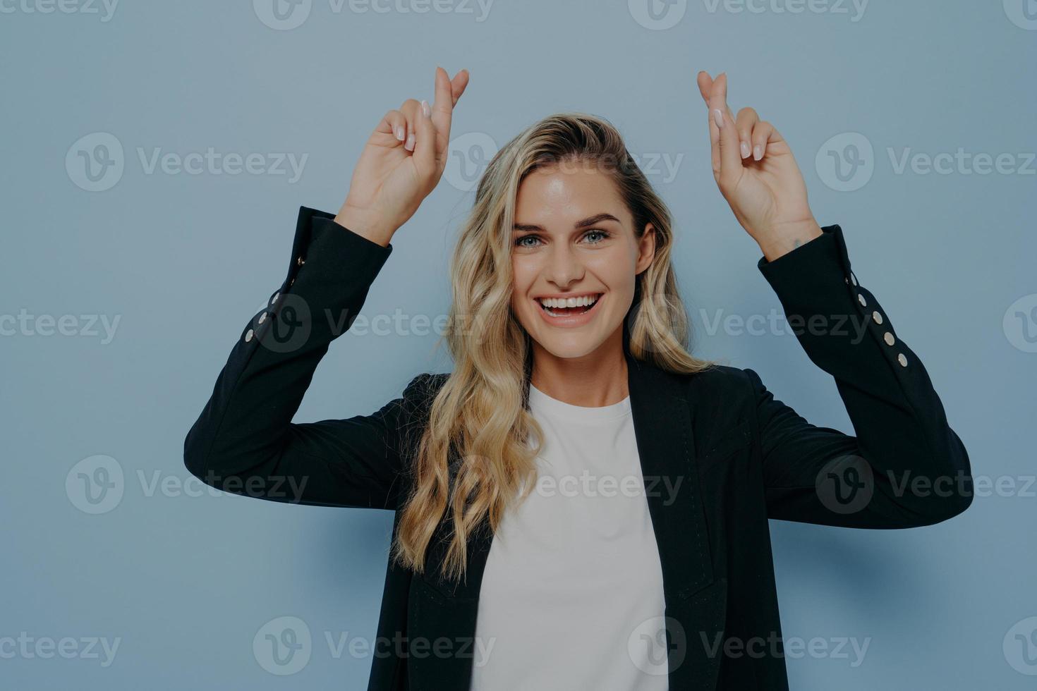 Excited blonde girl wishing with crossed fingers photo
