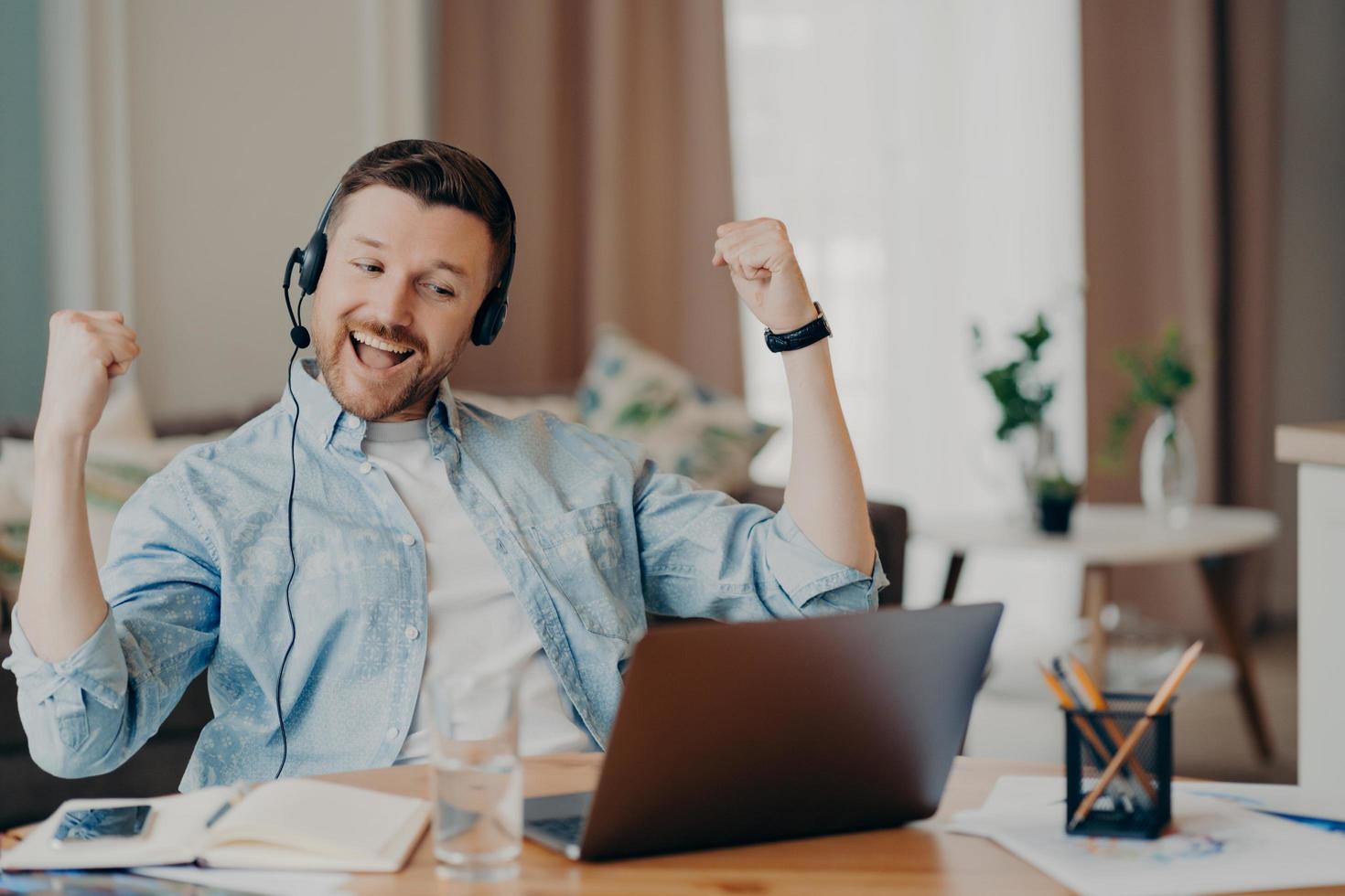 Handsome man enjoying victory while sitting at his workplace at home photo