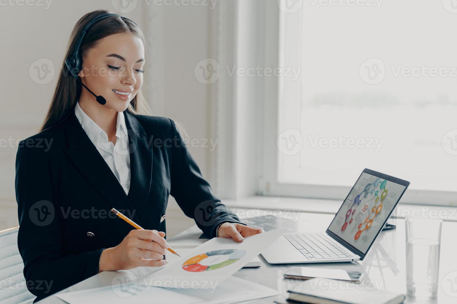 Satisfied female entrepreneur in headset analyzing project results during web conference photo