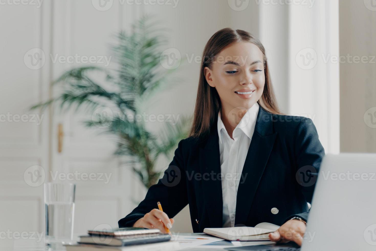 mujer de negocios feliz trabajando en una laptop en la oficina foto