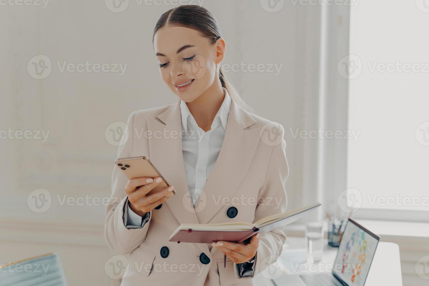 sonriente joven empresaria mirando la pantalla del teléfono inteligente foto