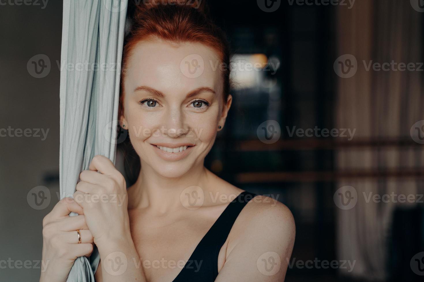 Young beautiful lady with red hair holding yoga hammock photo