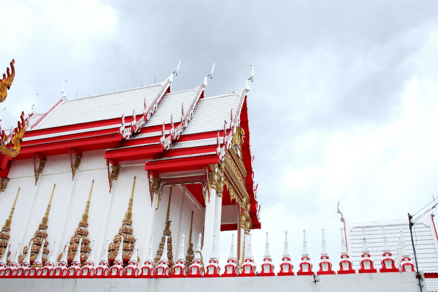 Beside red and white colr church in Thai ancient style of WatKhunyingsomjean and cloudy sky background, Thailnad photo