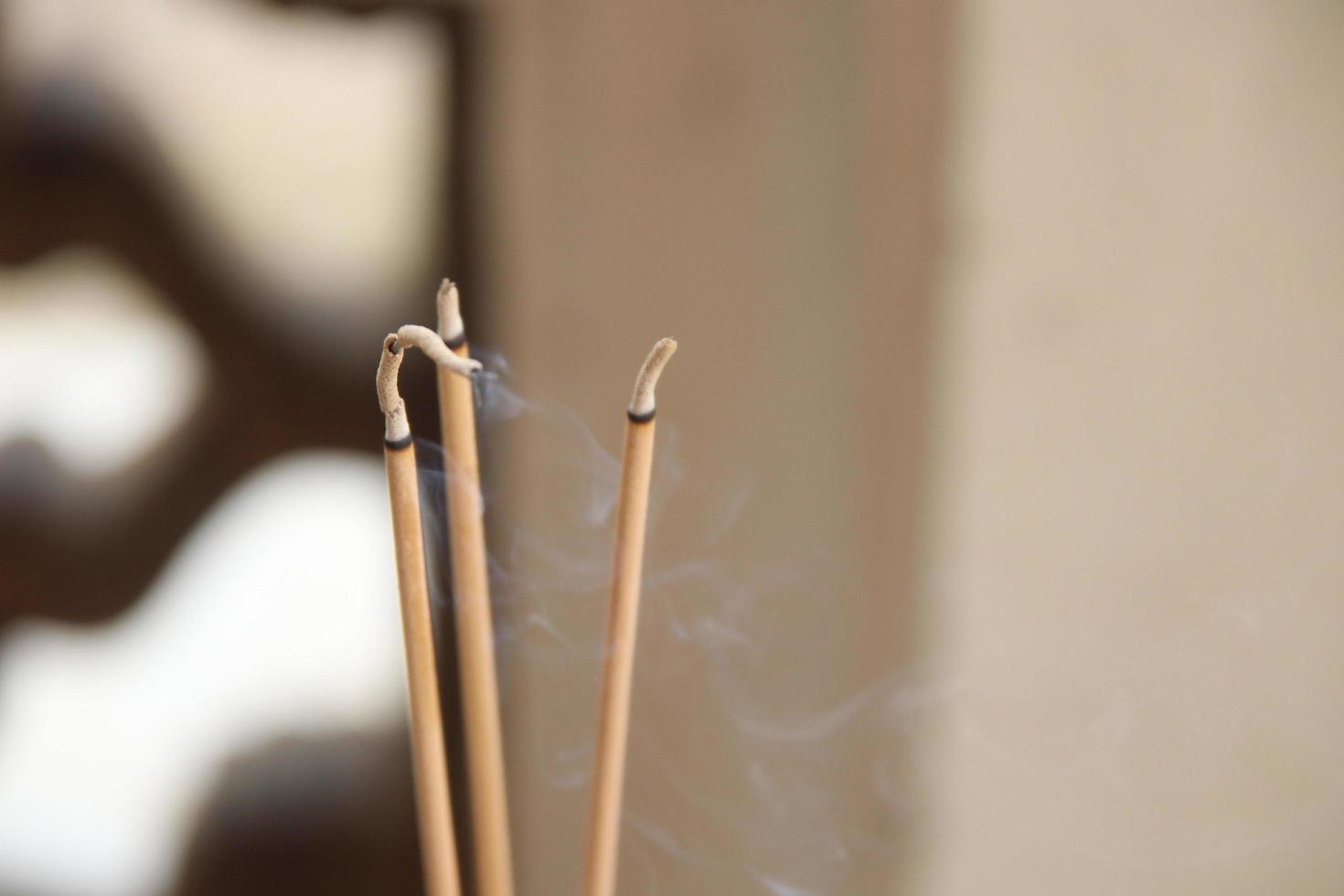 Incense sticks are burning and light brown background. Three incense sticks used pay respect Buddha statue. photo